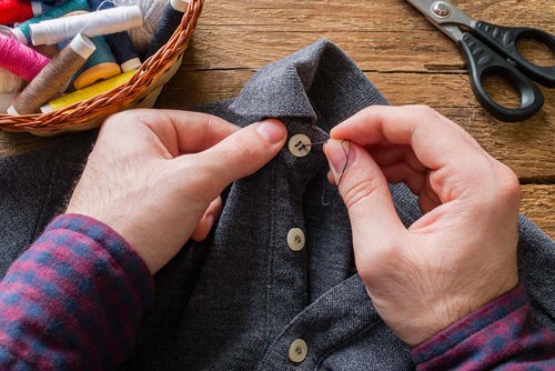 person sewing a button on a shirt