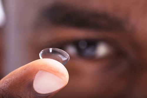 man holding contact lens on finger